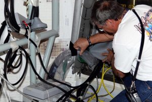 En tekniker kontrollerar delar av de tillfälliga ledningar som dragits in och ut i Atlantis under de senaste dagarnas felsökningsarbete. 