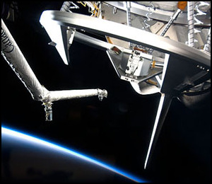 Discoverys dockningsmekanism fotograferad med jorden i bakgrundenm.